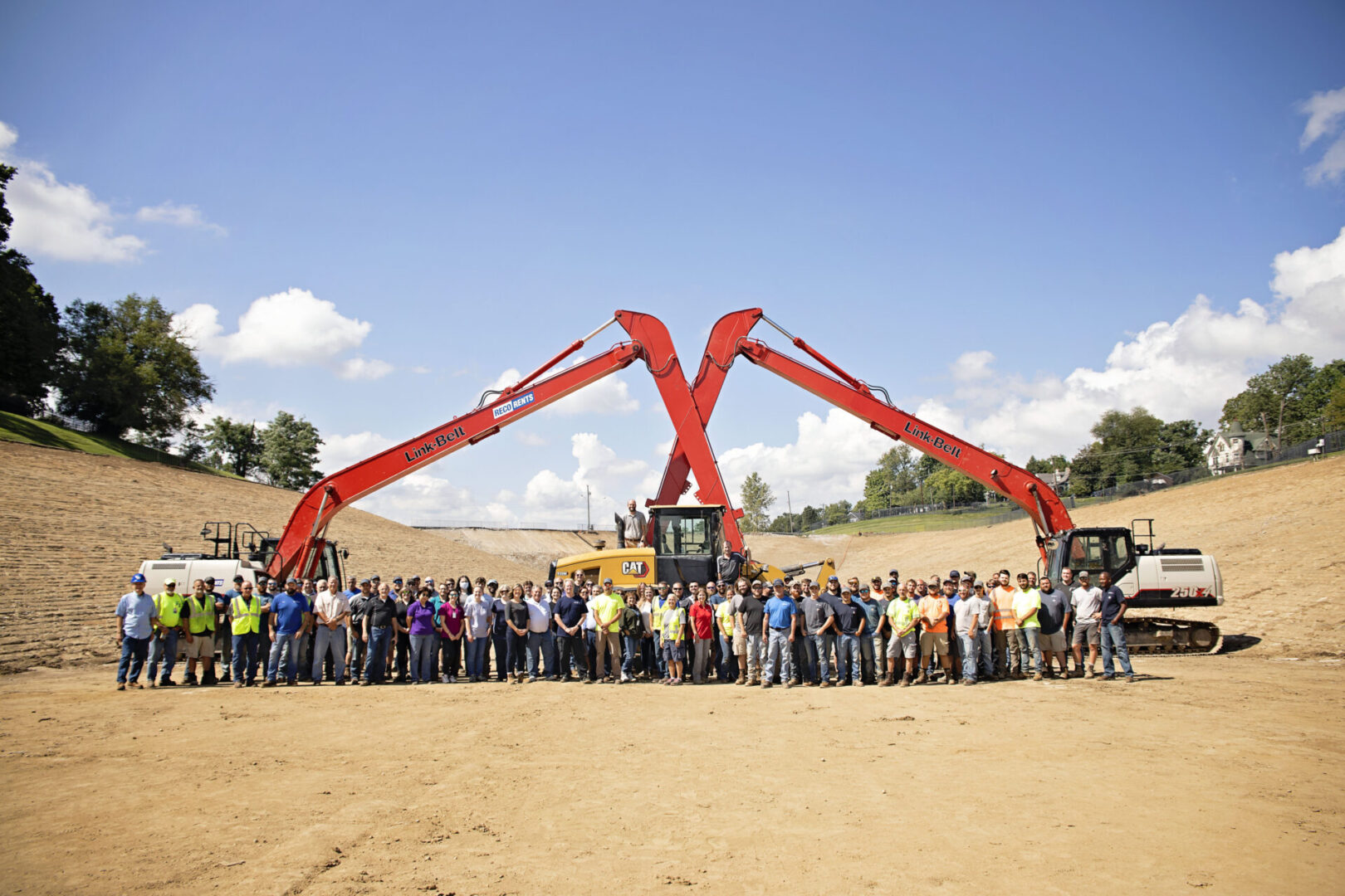 A large group of people and some heavy equipment on an empty piece of land